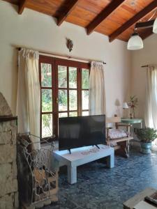 sala de estar con TV grande y mesa en LA CALANDRIA en Sierra de los Padres