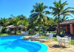 um resort com uma piscina com cadeiras brancas e palmeiras em Acquamarine Park Hotel em Guarapari