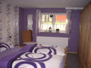een slaapkamer met een bed met paarse muren en een raam bij Holiday home Kobel in Elmstein