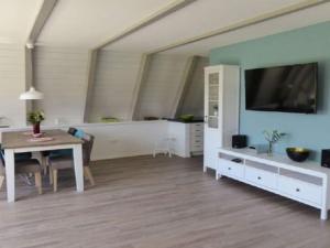 a living room with a table and a tv on a wall at Holiday home Sehnsucht Schlei in Brodersby +7 photos