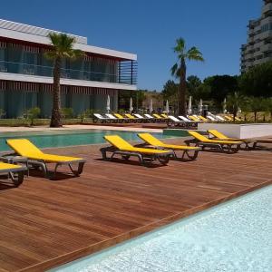 eine Reihe gelber Liegestühle neben einem Pool in der Unterkunft Pestana Alvor South Beach Premium Suite Hotel in Alvor