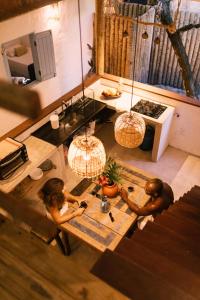 zwei Personen sitzen an einem Tisch in einer Küche in der Unterkunft Casinha do Rio in Caraíva