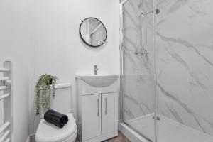 a bathroom with a shower and a toilet and a clock at Birkenhead Aparthotel in Rock Ferry