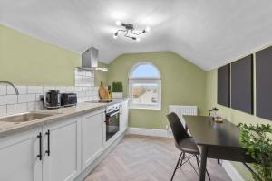 a kitchen with white cabinets and a table and a window at Birkenhead Aparthotel in Rock Ferry