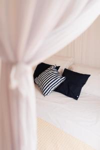 ein weißes Bett mit schwarzen Kissen darauf in der Unterkunft Villa Joá - Casa in Trancoso