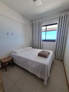 um quarto com uma cama branca e uma janela em Apartamento frente mar praia do flamengo em Salvador mais 18 fotografias