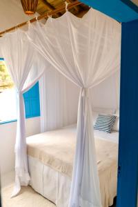 Bett mit Baldachin in einem Zimmer mit Fenster in der Unterkunft Villa Joá - Casa in Trancoso