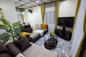 Il comprend un salon doté d'un canapé et d'une télévision à écran plat. dans l'établissement Entire 3-Bedroom Holiday Home in Kampala, Lovingly Furnished, à Kampala