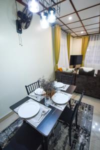 a dining table with plates and chairs and a living room at Entire 3-Bedroom Holiday Home in Kampala, Lovingly Furnished in Kampala