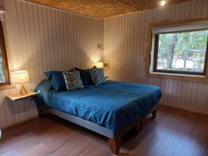 1 dormitorio con cama con sábanas azules y ventana en Conguillio cabaña Concón Turismo Conguillio, en Santa María