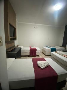 a room with three beds and a tv in it at Pousada Estrela Dalva in Penha