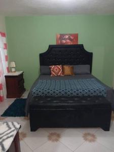 Schlafzimmer mit einem Bett mit einem schwarzen Kopfteil in der Unterkunft Willow tree quiet and peaceful in Montego Bay