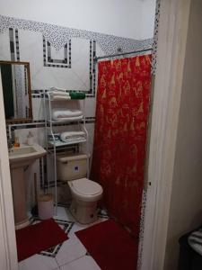 a bathroom with a toilet and a red shower curtain at Willow tree quiet and peaceful in Montego Bay