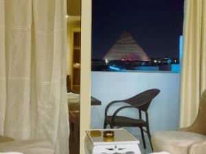 um quarto com uma cadeira e vista para a pirâmide em Pyramids Rose view no Cairo