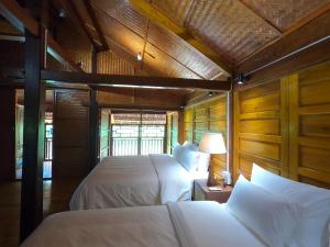 dwa łóżka w pokoju z drewnianymi panelami w obiekcie Luxury Traditional Chalet w mieście Hà Giang