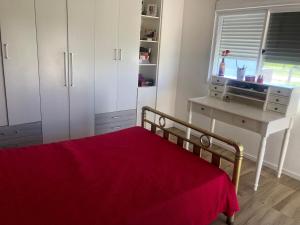 a bedroom with a bed with a red blanket at Casa das Maria Praia do Laranjal in Pelotas