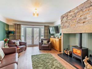 a living room with a fireplace and leather furniture at 3 Bed in Hamsterley 89896 in Witton le Wear