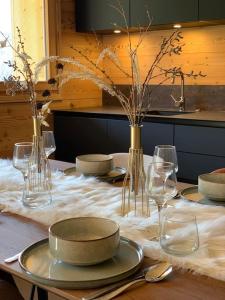 a table with plates and glasses on a table at Superbe chalet avec vue montagne in Orcières