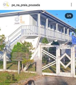 a white house with a white fence and a gate at Pousada Pé na Praia in Imbé