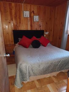 a bedroom with a bed with red pillows at Cabañas costa maule in Constitución