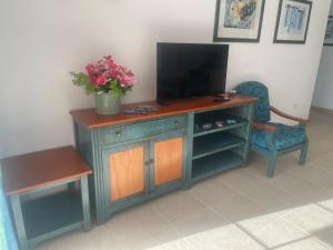 un centro de entretenimiento de madera con TV y silla en Sunset apartment en El Guincho