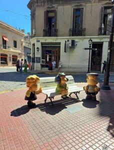 three stuffed animals standing around a bench on a street at La Casa de Malena in Buenos Aires