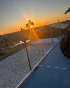 un court de tennis avec vue sur le coucher du soleil en arrière-plan dans l'établissement Pousada na fazenda! Venha descansar!, à Serra