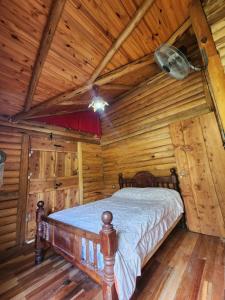 ein Schlafzimmer mit einem Bett in einer Blockhütte in der Unterkunft Talasuas -aires de montaña in Villa General Belgrano