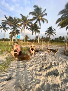 dos hombres y un perro en una playa con palmeras en Glamping La Isla Bonita (Isla Portete, Ecuador), en Zapotal