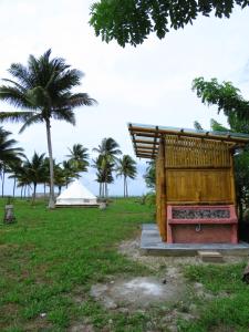 un bâtiment en bois dans un champ planté de palmiers dans l'établissement Glamping La Isla Bonita (Isla Portete, Ecuador), à Zapotal