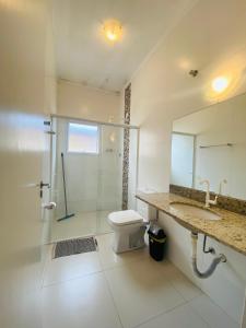 uma casa de banho com um WC, um chuveiro e um lavatório. em Suíte privativa próxima ao Sesc 1 em Bertioga