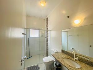 a bathroom with a sink and a toilet and a mirror at Suíte privativa próxima ao Sesc 1 in Bertioga