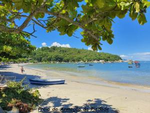 una playa con barcos en el agua y árboles en Casa completa - Governador Celso Ramos à 15min da praia de palmas, en Governador Celso Ramos