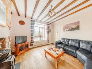 a living room with a black leather couch and a table at 3 Bed in Corwen 90459 in Corwen