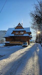 a large wooden house with a car parked in the snow at Niedźwiedzi szlak in Kościelisko