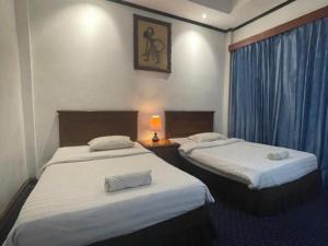 una habitación de hotel con 2 camas y una lámpara en Sadinah Sahid By Meliala, en Kartosuro