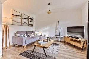 a living room with a couch and a tv at Maison de charme au coeur du marais breton Vendéen in Bouin