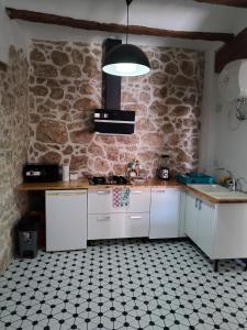 a kitchen with white cabinets and a stone wall at kats chulilla in Chulilla