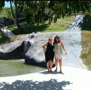 two women standing next to each other in front of a rock at Pousada Vila Sol Maior in Guarapari