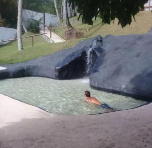 a man swimming in a swimming pool in a water park at Pousada Vila Sol Maior in Guarapari