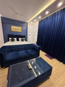 - une chambre avec un lit bleu et un canapé bleu dans l'établissement The Royal Residency Suites,Lucknow Gomti Nagar, à Lucknow