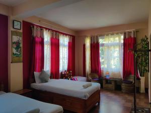1 dormitorio con 2 camas y cortinas rojas en The Shire Kalimpong en Kalimpong