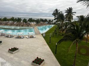 - une vue sur une piscine avec des tables et des palmiers dans l'établissement Maritima Playa Deluxe Ocean View Vallarta, à Nuevo Vallarta