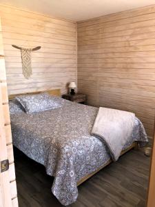 1 dormitorio con 1 cama y pared de madera en Cabañas Altos de Cahuil en Cáhuil