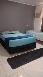 um quarto com 2 camas com lençóis azuis e um tapete em Casa em Angra dos Reis em Angra dos Reis