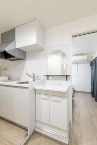 eine weiße Küche mit einem Waschbecken und einem Spiegel in der Unterkunft グランシャーギ in Osaka