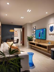 a living room with a couch and a tv on a wall at Apartamento Corais - Itacimirim Exclusive in Camacari