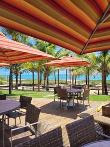 a patio with tables and chairs and umbrellas at Apartamento Corais - Itacimirim Exclusive in Camacari
