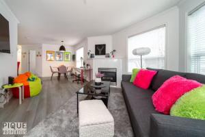 - un salon avec un canapé noir et des oreillers colorés dans l'établissement The Neon Palace - KingBed - Fireplace - Netflix - UG Park, à Edmonton