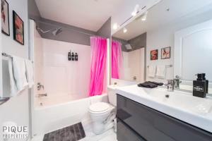 La salle de bains est pourvue d'un lavabo, de toilettes et d'une baignoire. dans l'établissement The Neon Palace - KingBed - Fireplace - Netflix - UG Park, à Edmonton